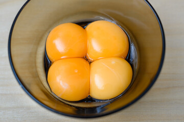 Bliskie zbliżenie na cztery nieugotowane, surowe, pomarańczowe żółtka jaj kurzych