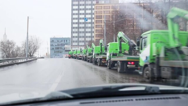 Green tow trucks on wet road on cold winter day in Moscow
