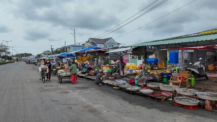 Daily life scene of vendors selling seafood at a traditional outdoor market in Asia on an overcast day