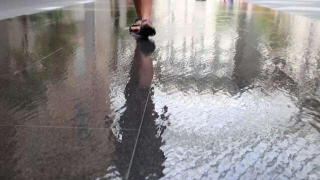 Feet of boy going on flow water on floor in buildings
