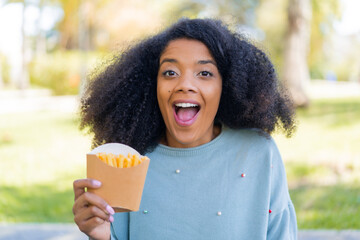 Young African American woman holding fried chips at outdoors with surprise and shocked facial...