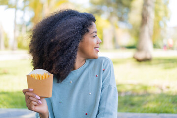 Young African American woman holding fried chips at outdoors in back position