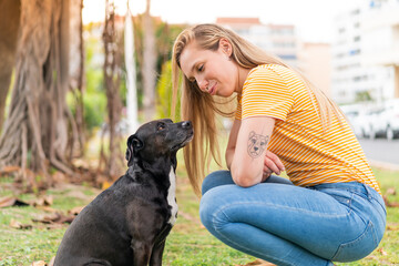 Young blonde woman with her adorable black dog at outdoors