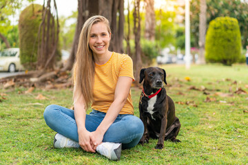 Young blonde woman with her adorable black dog at outdoors