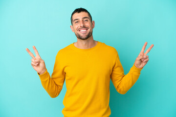 Young handsome caucasian man isolated on blue background showing victory sign with both hands