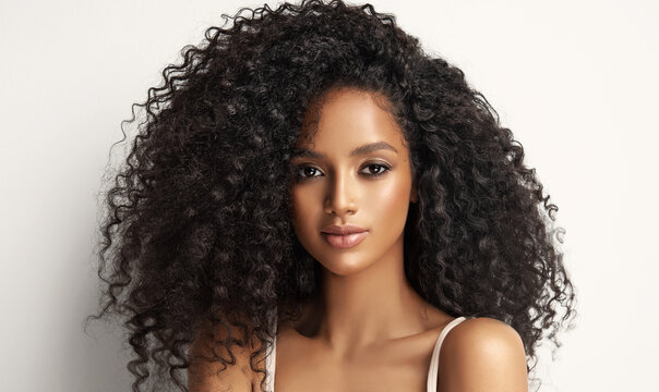 Beauty portrait of african american girl with clean healthy skin on beige background. Smiling dreamy beautiful black woman.Curly  hair in afro style 