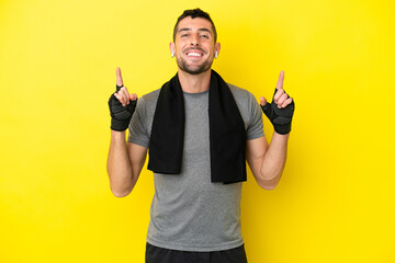 Young sport caucasian man isolated on yellow background pointing up a great idea