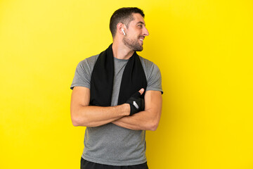 Young sport caucasian man isolated on yellow background with arms crossed and happy