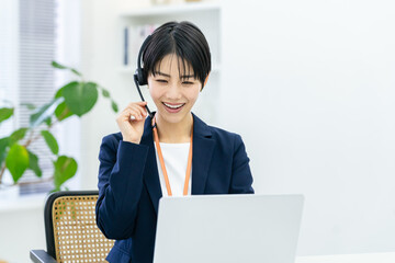 オフィスで仕事をするコールセンターの若い日本人女性