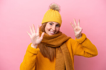 Young redhead woman wearing winter jacket isolated on pink background counting eight with fingers