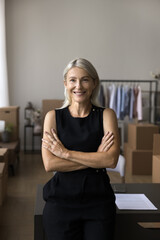 Small business owner portrait, individual entrepreneurship, dropshipping. Happy middle-aged businesswoman, designer posing with arms-crossed in own warehouse office smile look at camera, vertical shot