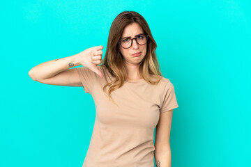Young caucasian woman isolated on blue background showing thumb down with negative expression