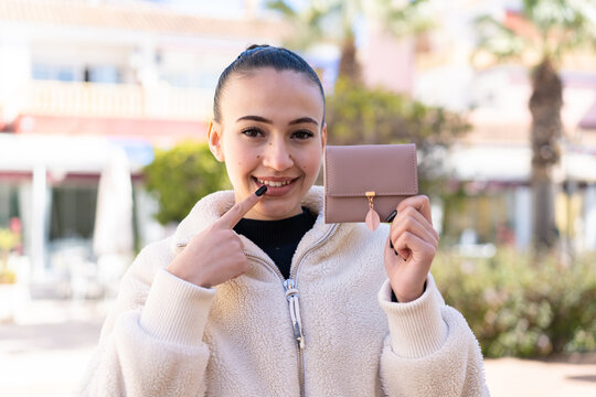 Young moroccan girl  at outdoors holding a wallet with happy expression