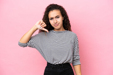 Young hispanic woman isolated on pink background showing thumb down with negative expression