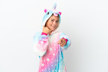 Little girl with unicorn pajamas isolated on white background making phone gesture and pointing front