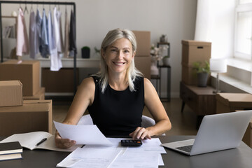 Happy successful mature businesslady, individual entrepreneur counting profit and incomes sit at...