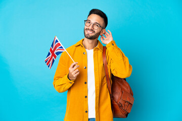 Young caucasian man holding an United Kingdom flag isolated on yellow background having doubts