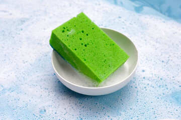 Bowl with cleaning sponge in foam of dishwashing liquid. Washing dishes concept