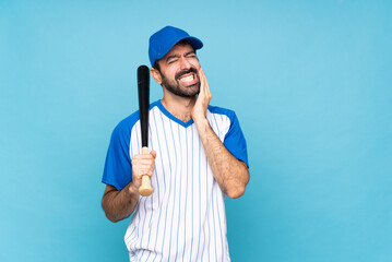 Young man playing baseball over isolated blue background with toothache