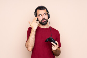 Man playing with a video game controller over isolated wall with problems making suicide gesture