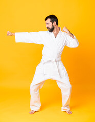 Full-length shot of man over isolated yellow background doing karate