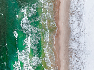 Aerial view of sea with snowy beach at winter.