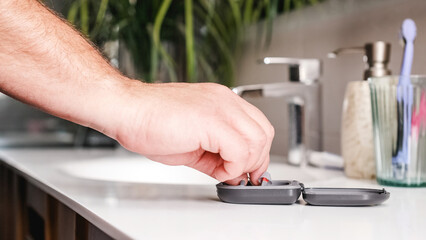 Adult man taking hearing aids from the bathroom