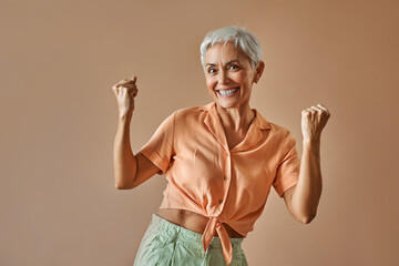 Portrait of a modern woman wearing an orange t-shirt and green pants of pastel shades who is...