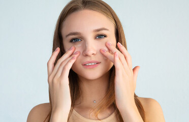 Fototapeta premium Young female smearing cream on face