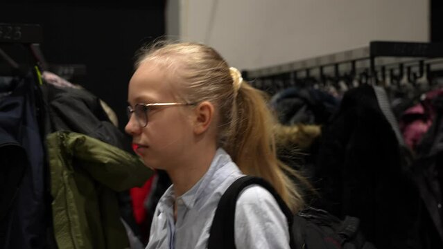 Close-up shot of blond hair schoolgirl leaving her jacket in the cloakroom.