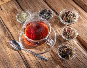 Cup of tea and dry teas on wooden background. Top view.
