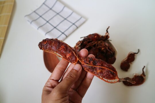 Asam Jawa or Tamarindus indica. Tamarind beans in a bowl on a white background, healthy fruit. Selective focus.