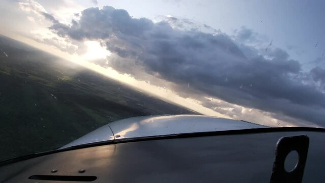 Student pilot flying towards sun shining through a hole in the clouds from pilot's POV.