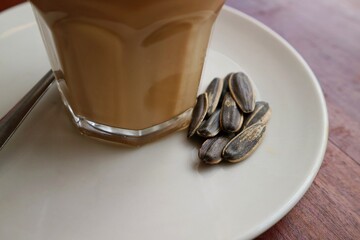 Kwaci ora kuaci on the coaster of a glass of coffee. Sunflower seeds is used as a snack to...