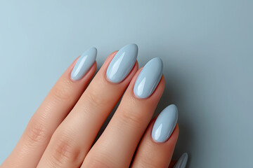  Close-up of woman fingers with beautiful blue  manicure. Pastel color nail manicure with gel polish at luxury beauty salon. 