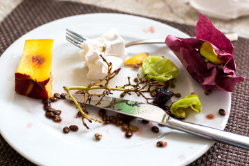 Fruit cores, leftover food and dirty napkins in a plate on the table.