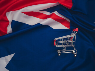 A small shopping trolley on the Australia flag background.