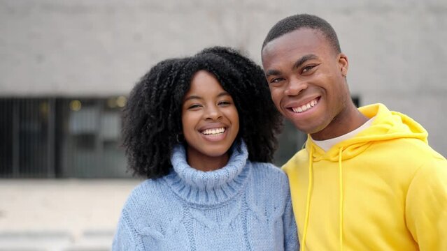 African young couple smiling at camera standing in the street