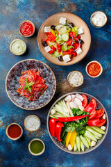 Dish with vegetables, peppers, tomatoes and greens, plates with vegetable salads and various types of sauces