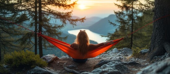 Young woman relaxing in hammock on top of the mountain at sunrise