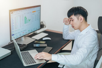 Handsome young businessman is trading the stock market via computer and smartphone.