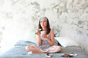 Cheerful sad young craing woman eating sweets in her bedroom