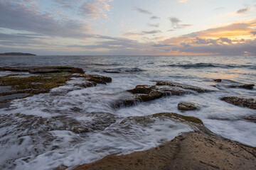 Rock formations on the coast with water flowing on them.