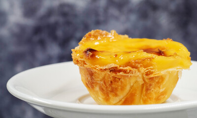 Plate with one Portuguese Pastel de Nata quiche. Pastel de Belem is a monastic and cult pastry in the form of cups with a burnt top and a crispy puff pastry crust. Sweet dessert with egg cream.