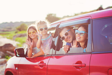 Portrait of a smiling family with two children at beach in the car - obrazy, fototapety, plakaty