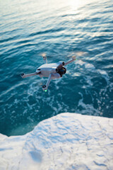 A quadcopter in flight against the background of a beautiful sea and white cliffs in the sunset light