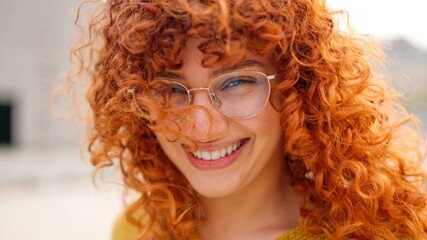 Redhead woman with curly long hair smiling at camera
