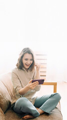Joyful millennial woman with an open mouth, captivated by her phone. Engaged in playing mobile games, reading messages, and lively chatting in a chat room. Expressive Smartphone Interaction.