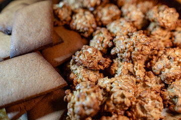 Crispy oatmeal cookies and other brown homemade cookies in a plate. Delicious snack for treating guests and supplement for tea or coffee.