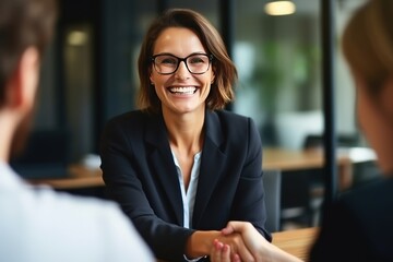 Middle aged Caucasian businesswoman in eyeglasses handshaking at office meeting. Cheerful female HR hiring recruit at job interview, bank or insurance agent. Lawyer making contract deal with client. - obrazy, fototapety, plakaty